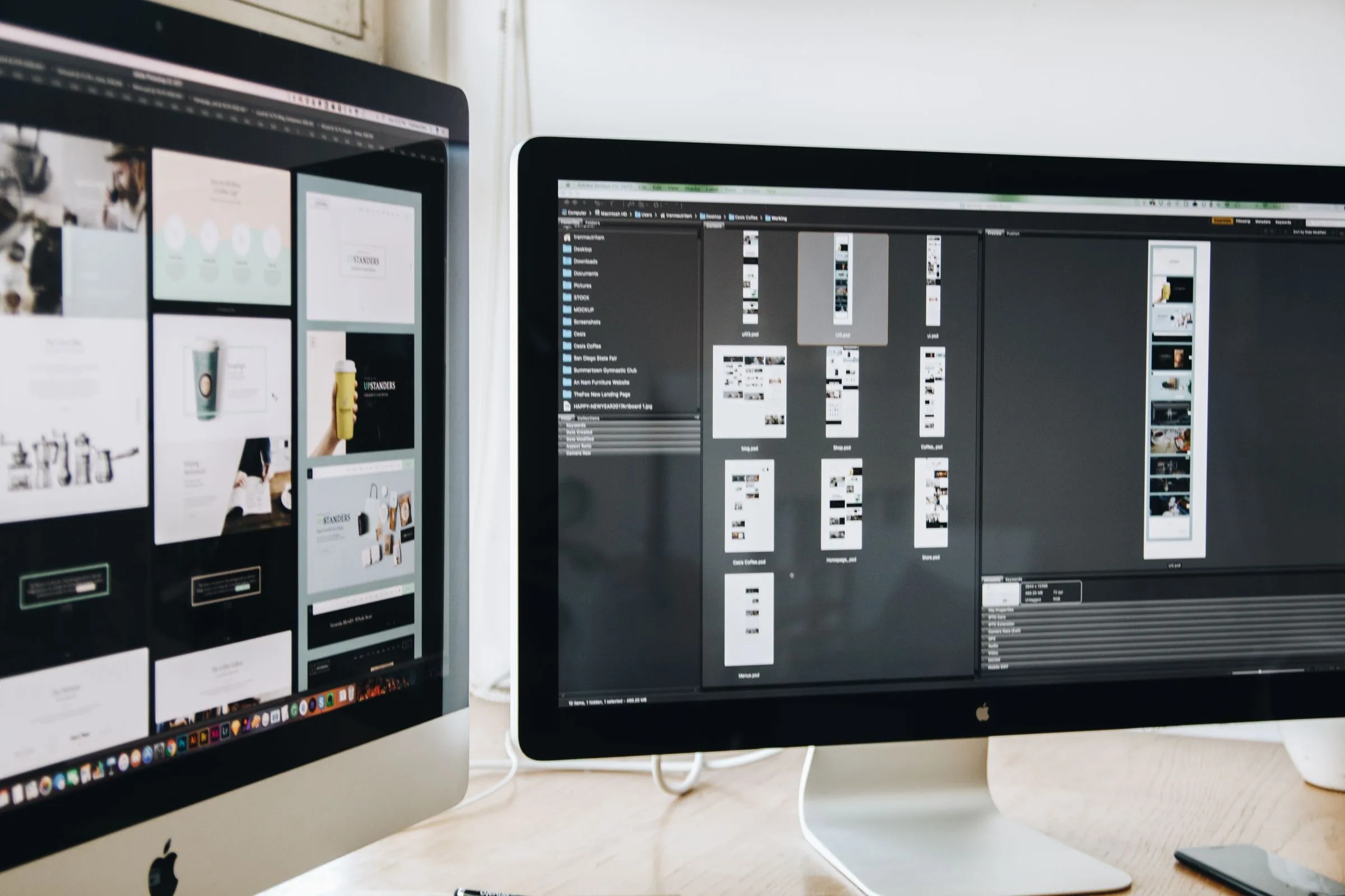 A designer's desk with website layouts on one monitor and design software on the other