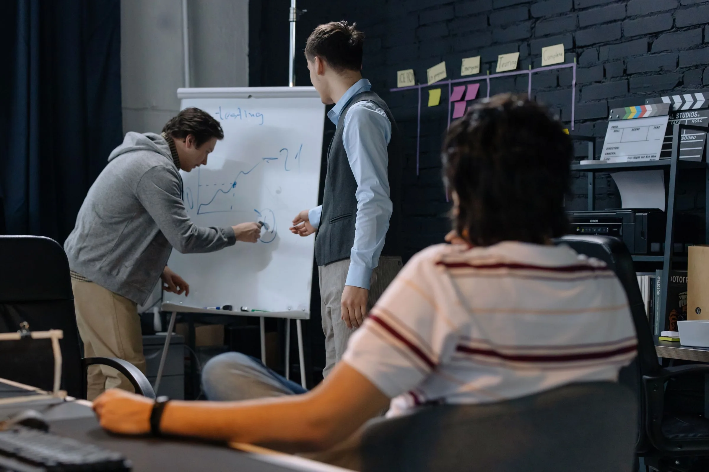 A product team plans the scope of an MVP at a whiteboard, one person sketching while two colleagues discuss